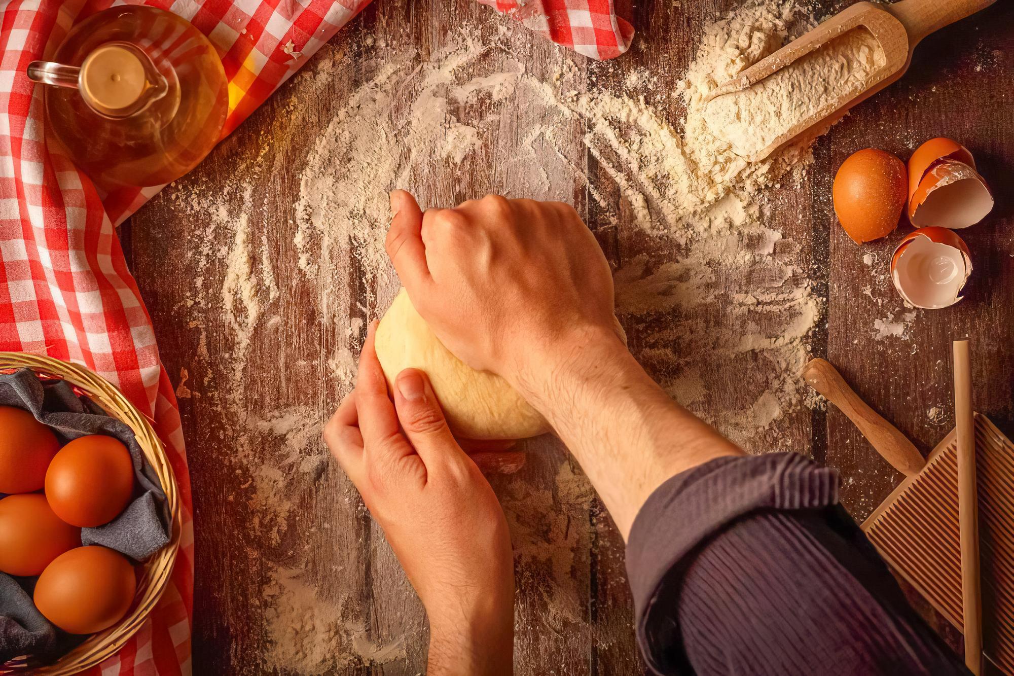 Hands kneading dough on wooden table